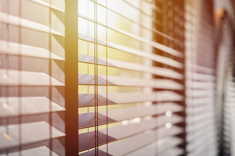 Jasne światło przeszywające żaluzje okienne
