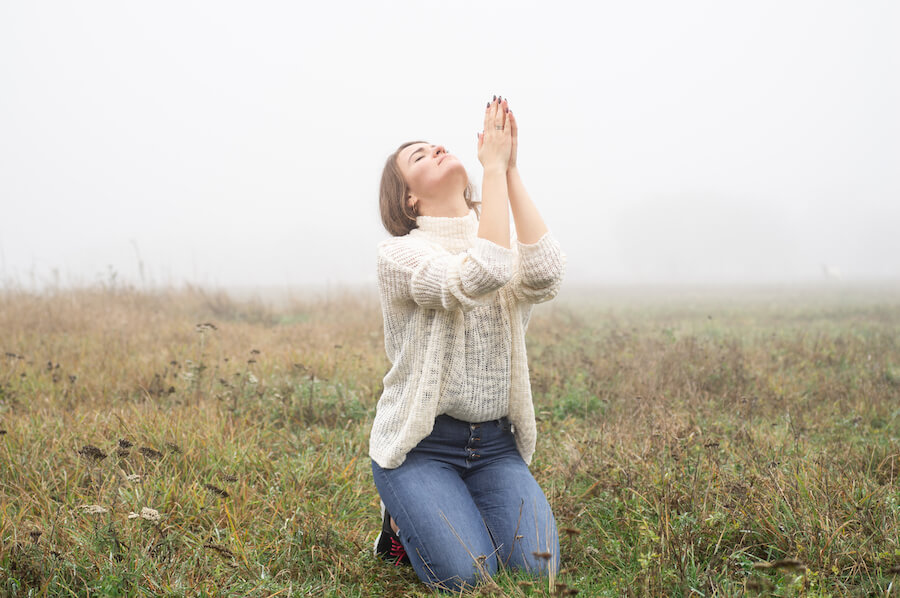 Kobieta modląca się na kolanach na łące Kobieta modląca się na kolanach na łące